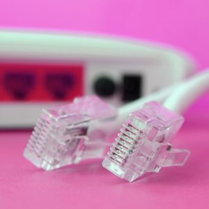Internet router and Internet cable plugs lie on a bright pink background. Items required for Intern